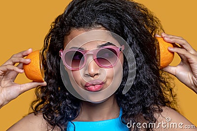 Pretty young woman in sunglasses with orange in hands Stock Photo