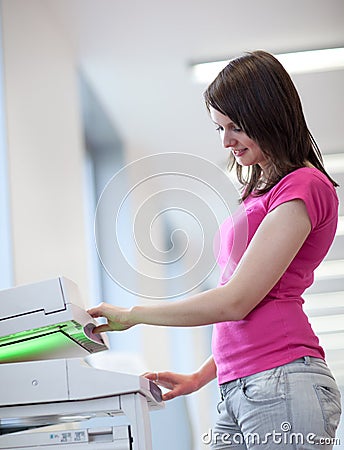 Pretty young woman using a copy machine Stock Photo