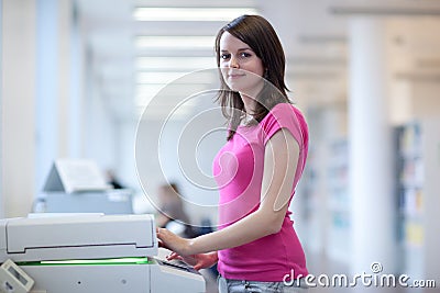 Pretty young woman using a copy machine Stock Photo