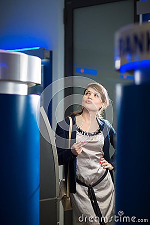 Pretty, young woman withdrawing money from her credit card Stock Photo