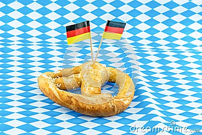 Pretzel with salt and a pair of germany flag on munich background blue rhombus pattern Stock Photo