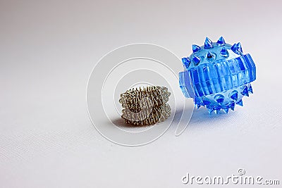 A prickly plastic blue massage ball isolated against a light background. Next to the ball are prickly rings for Stock Photo