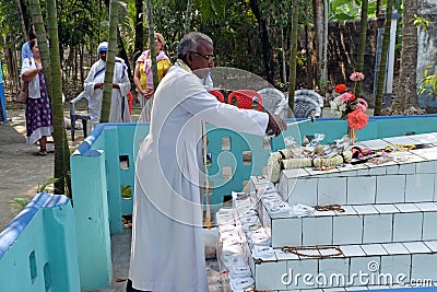 The priest blesses religious objects at the tomb of a Croatian missionary, Jesuit father Ante Gabric in Kumrokhali, India Editorial Stock Photo