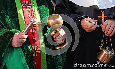 priest with cassock and aspergillum while performing the blessing also with holy water and incense during the holy mass Stock Photo