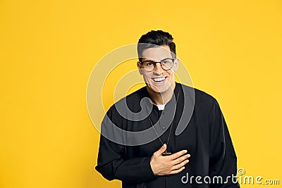 Priest in cassock with clerical collar laughing on yellow Stock Photo