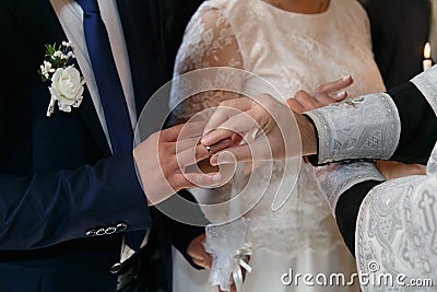 The priest changes the wedding rings on the fingers of the bride and groom. Stock Photo