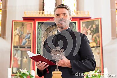 Priest in church with bible in front of altar Stock Photo