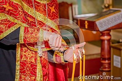 Priest hand burning hair in candle light Stock Photo