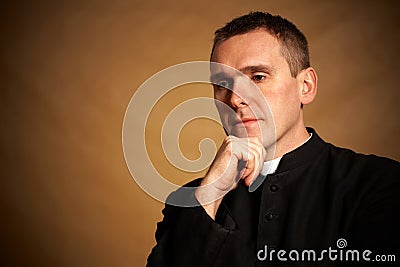 Priest with hand under chin Stock Photo