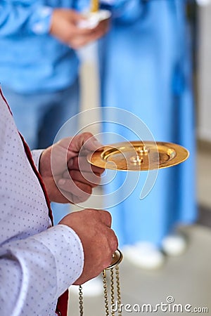 A priest holds a gold plate with wedding rings at a wedding ceremony in a church Stock Photo