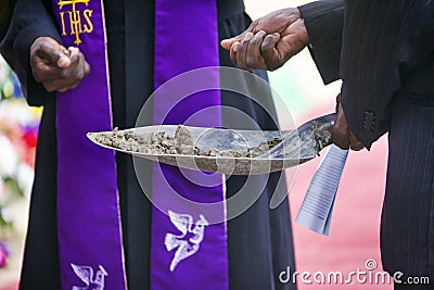 priest and mourner holding a spade with ground to bless the grave Stock Photo