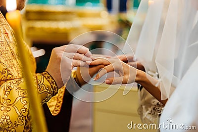 Priest puts on ring on brides finger during church wedding ceremony. Exchange of rings. Horizontal view. Marriage concept Stock Photo