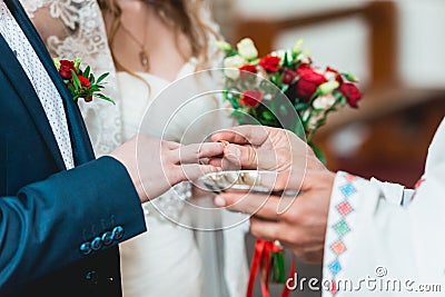 Exchanging wedding rings. priest putting on golden wedding rings on fingers bride and groom in church at wedding matrimony Stock Photo