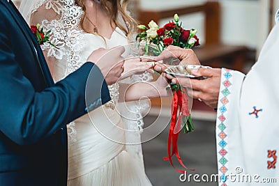 Exchanging wedding rings. priest putting on golden wedding rings on fingers bride and groom in church at wedding matrimony Stock Photo