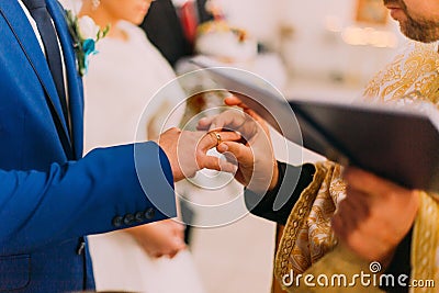The priest putting a ring on groom's finger during traditional wedding in church Stock Photo