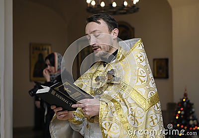 Priest reading Bible in a rural church. Baptizing for baby Editorial Stock Photo