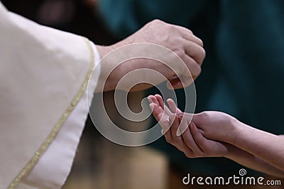 Priest serving holy communion placing the bread in the hands of the parishioner Stock Photo