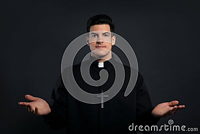 Priest wearing cassock with clerical collar on black Stock Photo