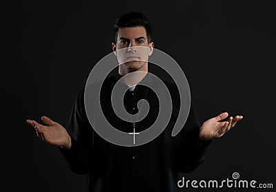 Priest wearing cassock with clerical collar on black background Stock Photo