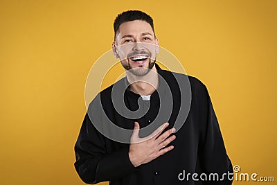 Priest wearing cassock with clerical collar on yellow background Stock Photo