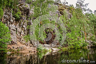 Primal rock on the shore of a calm lake Stock Photo