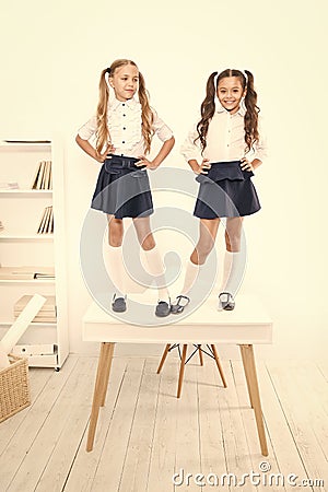 Primary school fashion. Happy school kids with fashion look standing on table. Fashion small girls with long hair Stock Photo