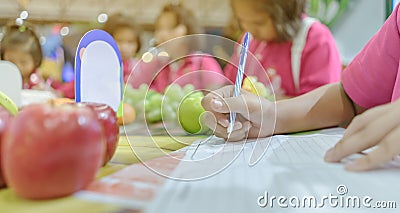 Primary school girls learn and take notes about different types of fruits Stock Photo