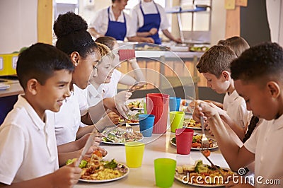 Primary school kids eating at a table in school cafeteria Stock Photo