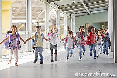 Primary school kids run holding hands in corridor, close up Stock Photo