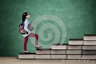 Primary student lifting hands with books on desk Stock Photo