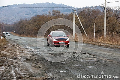 Primorsky Krai, Russia - 2016, autumn - A car drives along a bad, dead road among tall trees. Russian roads. Bad asphalt Editorial Stock Photo