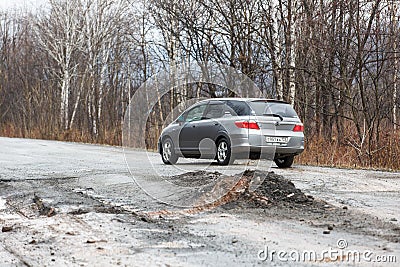 Primorsky Krai, Russia - 2016, autumn - A car drives along a bad, dead road among tall trees. Russian roads. Bad asphalt Editorial Stock Photo
