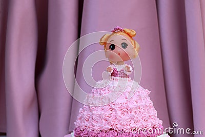 Princess doll cake with dress made of cream on pink curtain background Stock Photo