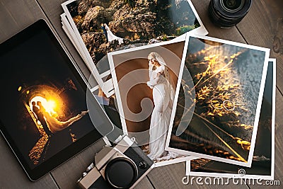 Printed wedding photos with the bride and groom, a vintage black camera and a black tablet with a picture of a wedding Stock Photo