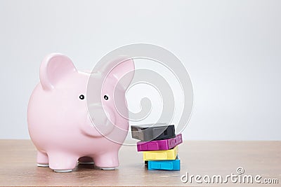 Printer cartridges next to piggy bank Stock Photo