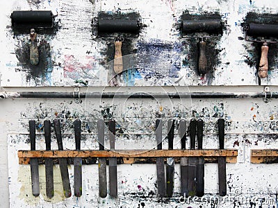 Printmaking rollers hanging on an art studio wall in the messy workshop Stock Photo