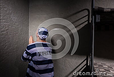 Prisoner is sitting in the corner and praying in a small prison Stock Photo