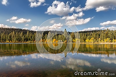 Pristine view of a mirror lake on a crisp autumn day with mountains and fall foliage. Stock Photo