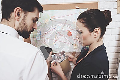 Private detective agency. Man and woman are looking at map, discussing clues. Stock Photo