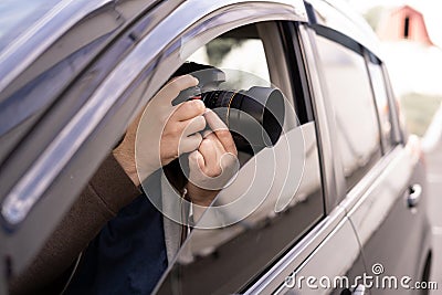 Private detective or investigator or paparazzi taking photos on street while sitting in car Stock Photo