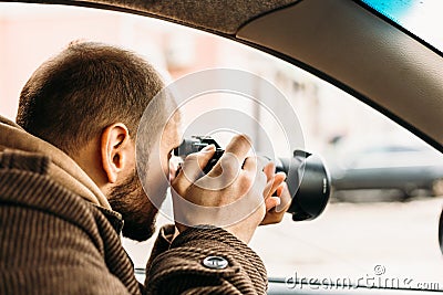 Private detective or reporter or paparazzi sitting in car and taking photo with professional camera Stock Photo