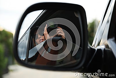 Private detective with camera spying from auto, view through car side mirror Stock Photo