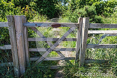 Private farm land fenced off by a large gate with a private keep out sign showing no access to the rural pathway Stock Photo