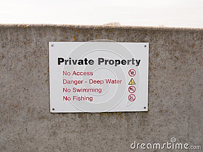 Private property sign on grey sea wall barricade no permission Stock Photo
