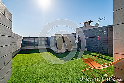 Private terrace with sunbeds, kids soccer gates and artificial turf on sunny day with blue sky. Stock Photo