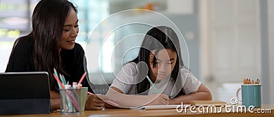 Private tutor and student homeschooling on wooden table with stationery in living room Stock Photo