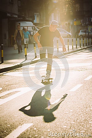 Pro skateboard rider in front of car on city street Stock Photo