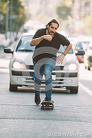 Pro skateboard rider in front of car on city street Stock Photo