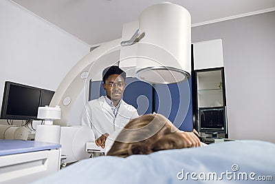 Procedure of extracorporeal shock wave lithotripsy in modern urology medical center. Young African man doctor providing Stock Photo