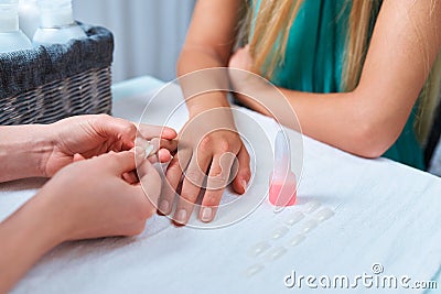 Procedure gluing artificial nails. manicure sticks nail on finger client. Stock Photo